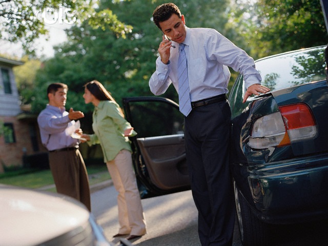 Businessman talking on his cell phone by a car accident